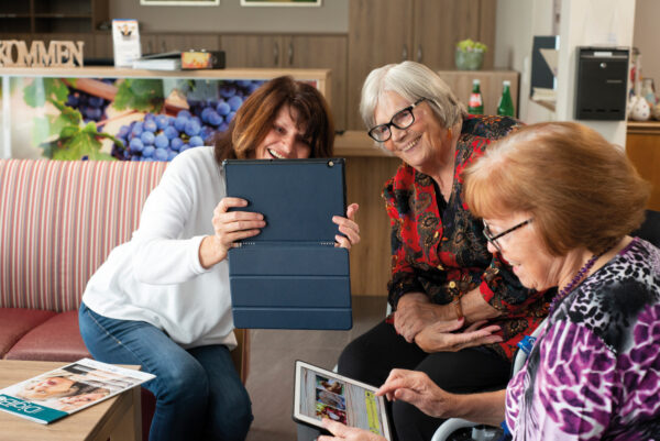 Drei Frauen sietzen auf einer Couch und machen mit einem Tablet ein Foto.