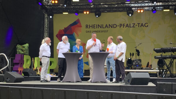 Minister Schweitzer mit Digitalbotschafterinnen und -Botschaftern, auf einer Bühne des RLP-Tags 2023